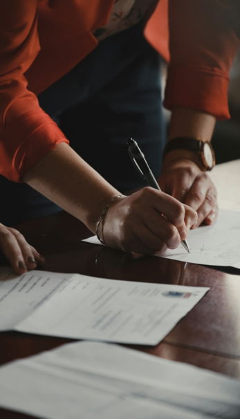 person-in-orange-long-sleeve-shirt-writing-on-white-paper.jpg person in orange long sleeve shirt writing on white paper